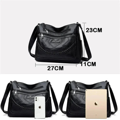 Black leather crossbody bag with front zipper pocket and braided trim, adjustable strap