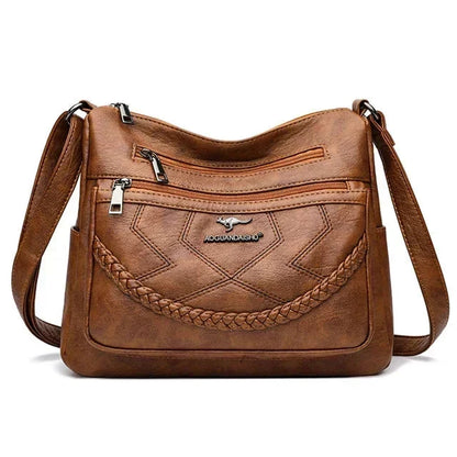 Brown leather crossbody bag with braided front, two zip pockets, adjustable shoulder strap