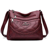 Burgundy leather crossbody bag front with braided panel, zip pockets, adjustable strap
